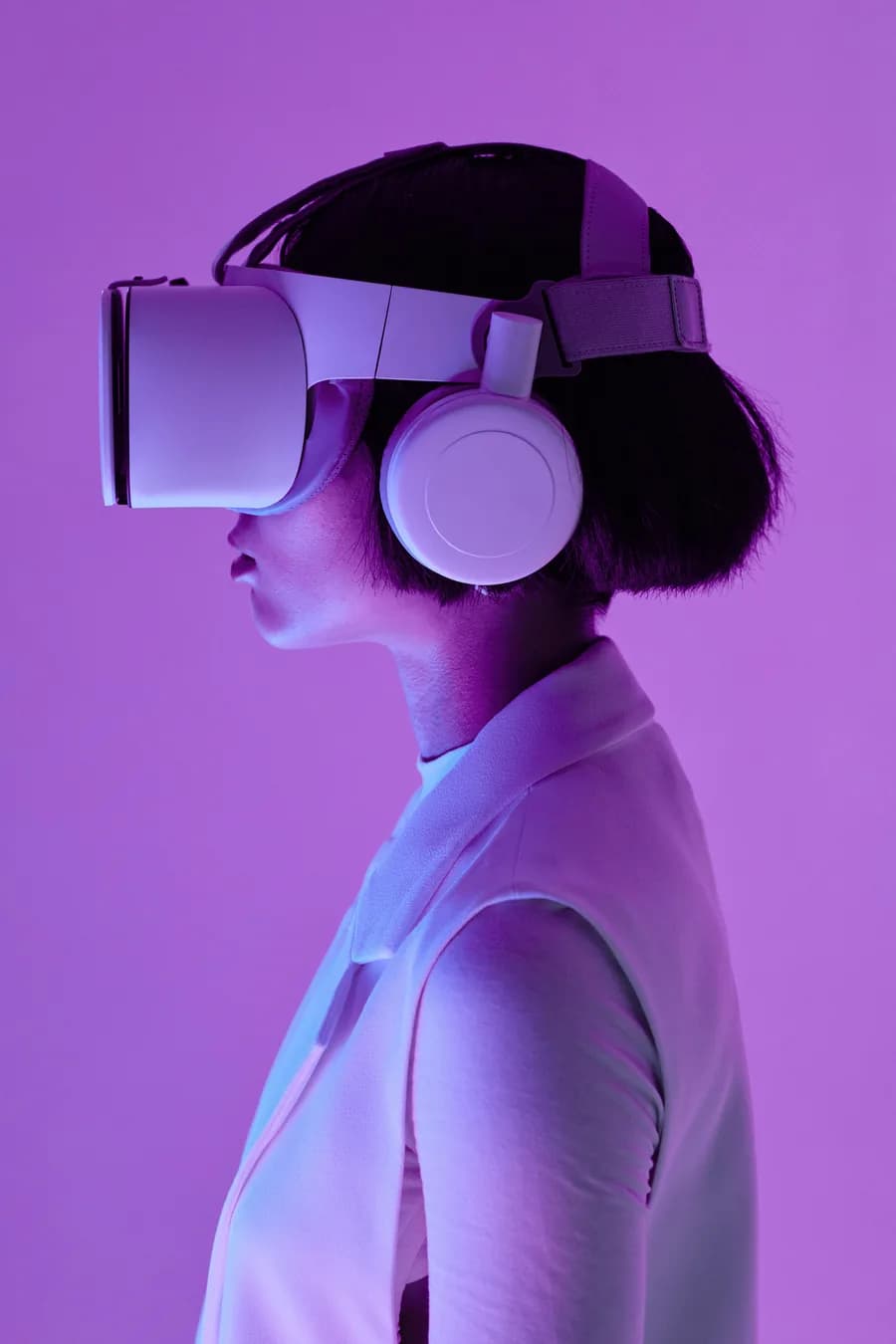 Person in profile wearing a VR headset and headphones against a purple background